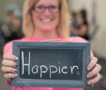 Woman holding sign that says happier