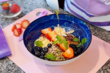 A nutritious breakfast bowl filled with Greek yogurt, fresh strawberries, blueberries, seeds, mint, and a drizzle of raw honey. Recipe from the Curves Pure 30 Challenge